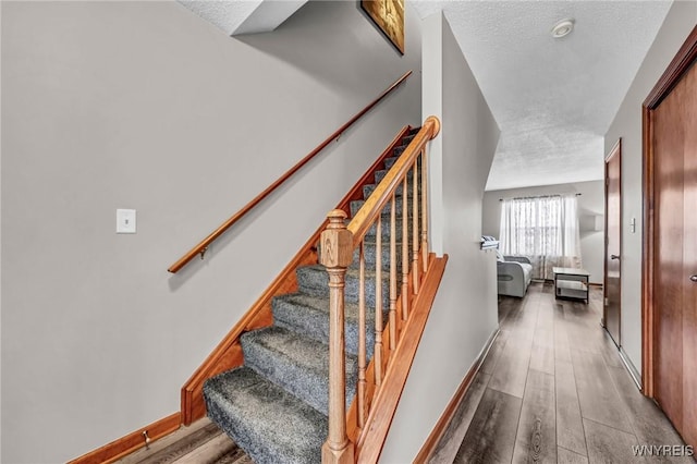 staircase featuring wood-type flooring and a textured ceiling