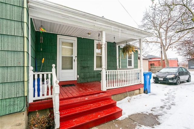 snow covered property entrance featuring a porch