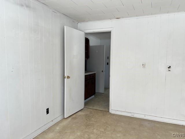 unfurnished bedroom featuring wooden walls and concrete flooring
