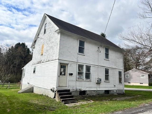 back of property with a yard and entry steps