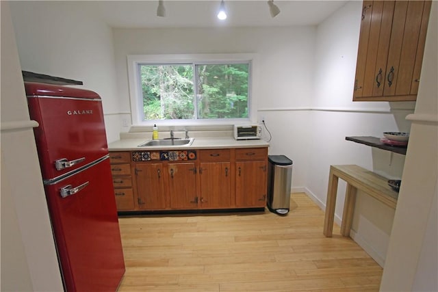 kitchen with refrigerator, sink, and light wood-type flooring