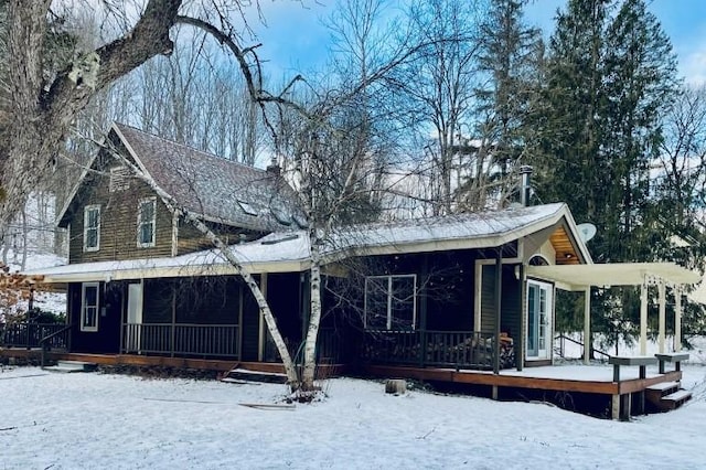 snow covered rear of property with covered porch