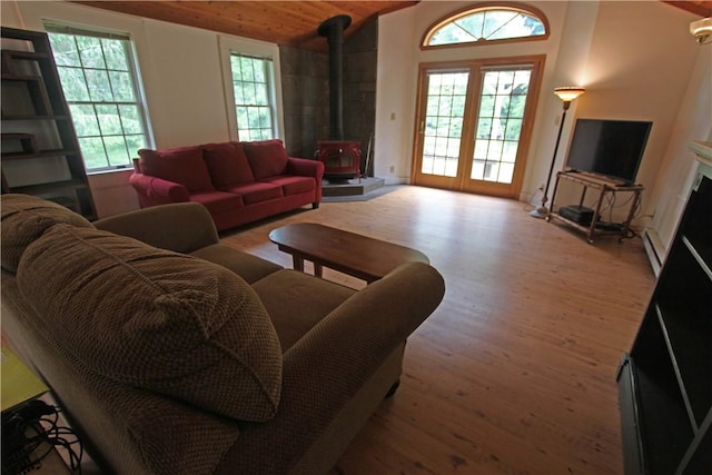 living room featuring hardwood / wood-style flooring, lofted ceiling, a healthy amount of sunlight, and a wood stove