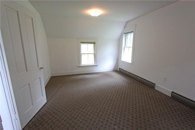 carpeted empty room with vaulted ceiling and baseboard heating