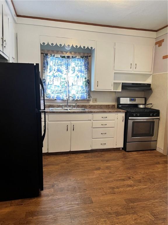 kitchen featuring stainless steel range with gas cooktop, black refrigerator, sink, white cabinets, and wall chimney exhaust hood