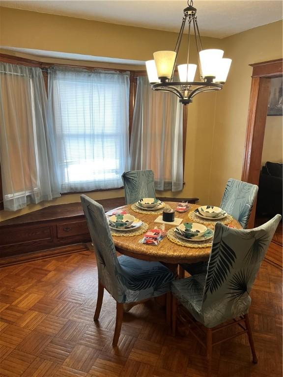 dining space featuring dark parquet floors and a chandelier