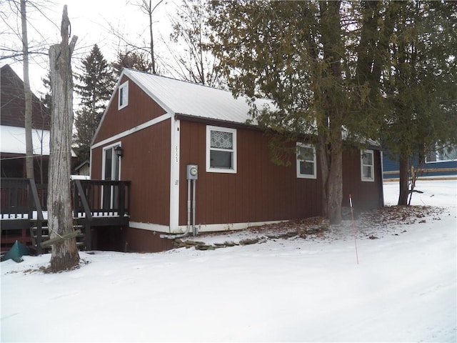 snow covered property with metal roof and a wooden deck