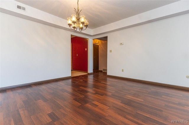 spare room featuring dark hardwood / wood-style floors and a chandelier