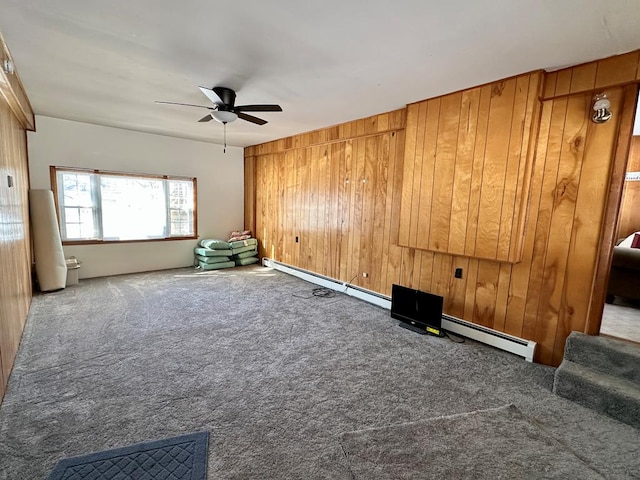 spare room featuring a baseboard radiator, carpet flooring, ceiling fan, and wooden walls