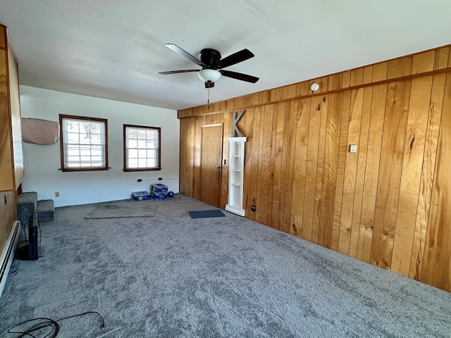 carpeted spare room with ceiling fan and wood walls