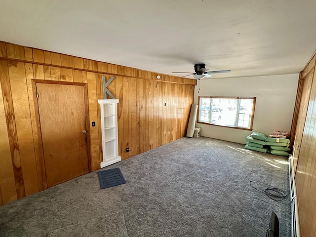 carpeted empty room featuring ceiling fan and wood walls