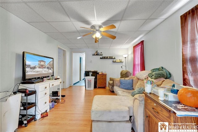 living room featuring a drop ceiling, light hardwood / wood-style flooring, and ceiling fan