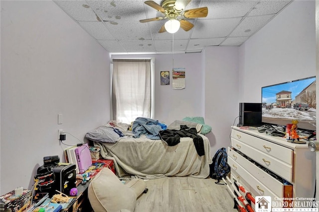 bedroom with hardwood / wood-style flooring, ceiling fan, and a drop ceiling