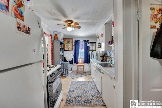 kitchen featuring gas range, sink, white fridge, and white cabinets