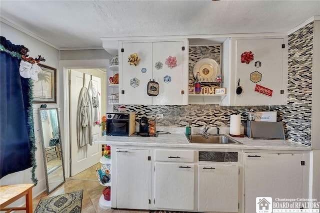 kitchen featuring sink, a textured ceiling, light tile patterned floors, white cabinets, and backsplash