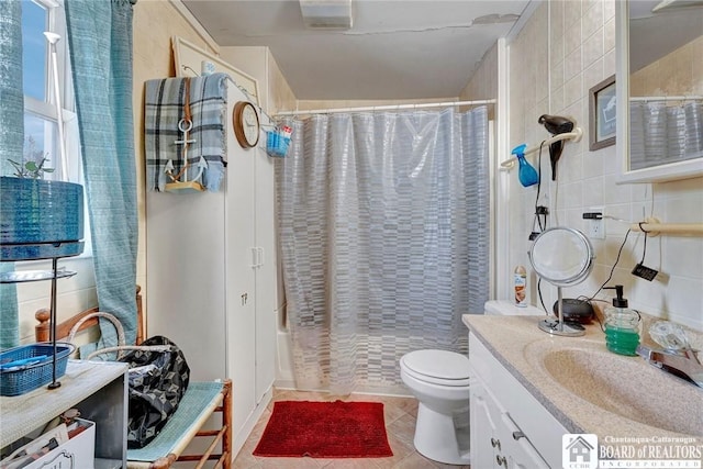 full bathroom featuring shower / bathtub combination with curtain, tile patterned flooring, tile walls, vanity, and toilet