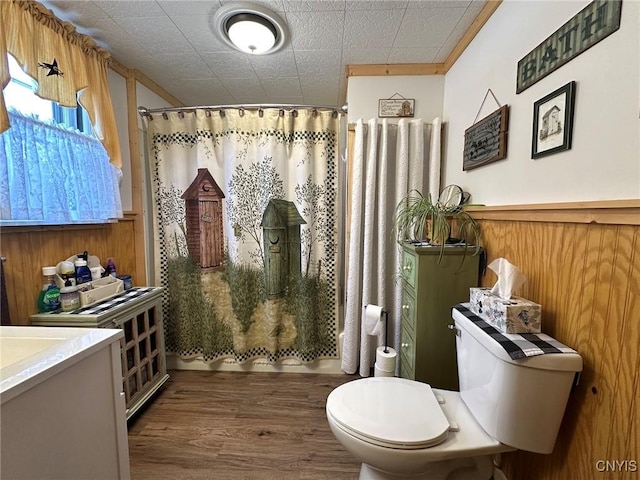 full bathroom featuring hardwood / wood-style floors, vanity, shower / bath combination with curtain, toilet, and wood walls