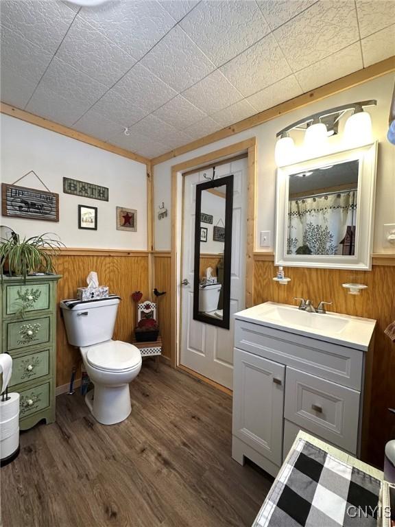 bathroom featuring vanity, toilet, wood-type flooring, and wood walls