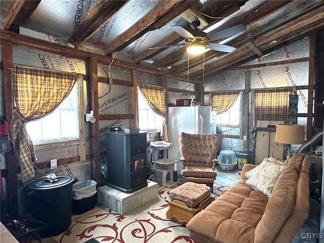 interior space featuring a wealth of natural light, lofted ceiling with beams, ceiling fan, and a wood stove