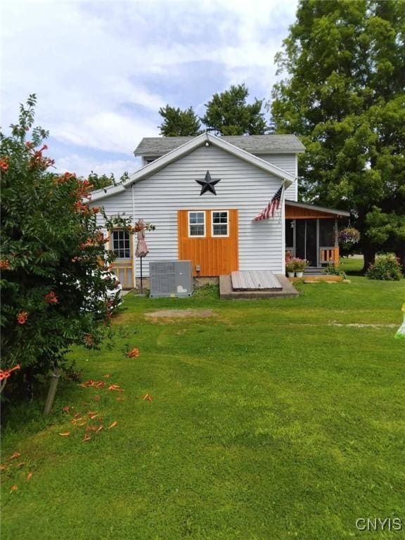 rear view of property featuring an outdoor structure, central AC, and a lawn