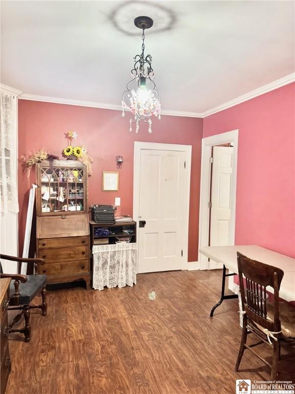 interior space featuring wood-type flooring, ornamental molding, and an inviting chandelier