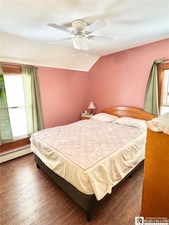 bedroom featuring ceiling fan, dark hardwood / wood-style flooring, vaulted ceiling, and a baseboard heating unit