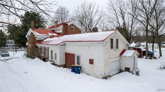 view of snow covered exterior with a garage and metal roof