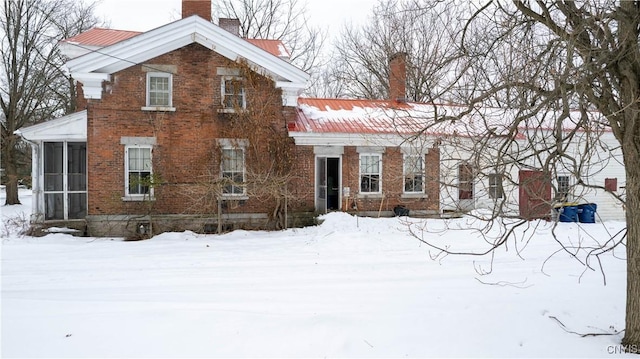 view of front of property featuring a sunroom, a chimney, and brick siding