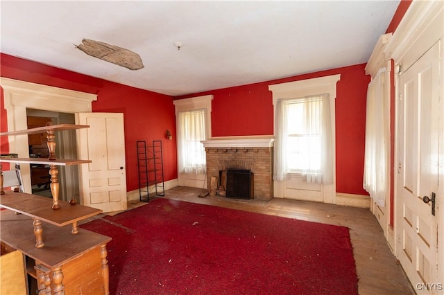 unfurnished living room with a brick fireplace and baseboards