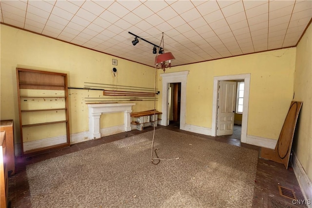 unfurnished living room featuring track lighting, baseboards, and crown molding