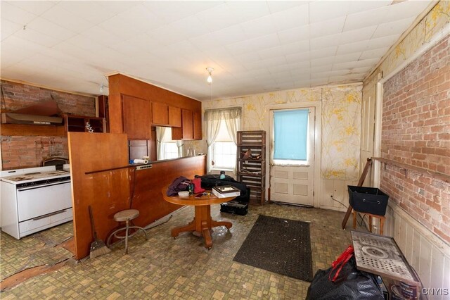 kitchen with brown cabinets, white electric stove, and brick wall