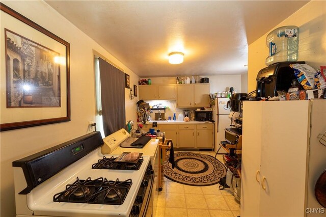 kitchen featuring light tile patterned flooring, black microwave, light countertops, and white gas range oven