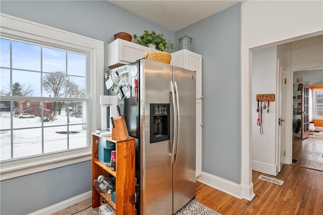 kitchen with white cabinetry, washer / dryer, stainless steel fridge, and light hardwood / wood-style floors