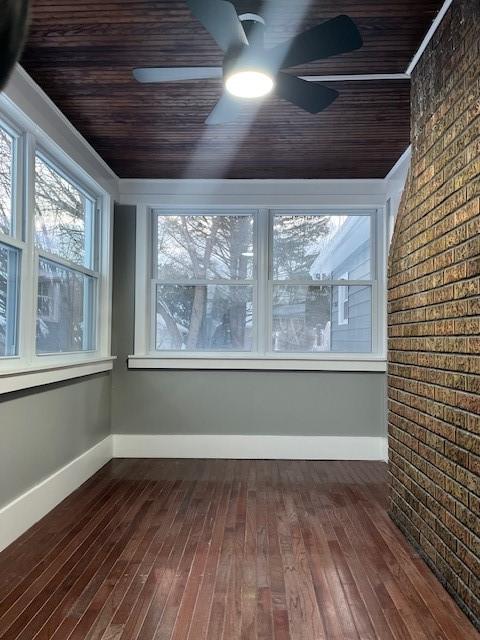 unfurnished sunroom featuring wood ceiling and ceiling fan