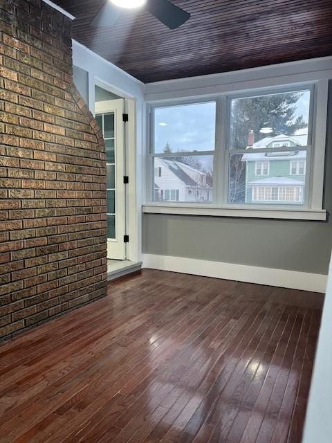 interior space featuring ceiling fan, brick wall, dark hardwood / wood-style floors, and wood ceiling