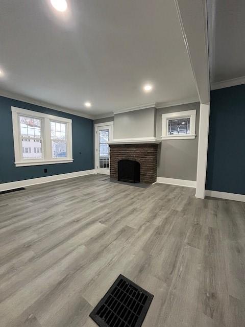 unfurnished living room featuring crown molding, wood-type flooring, and a fireplace