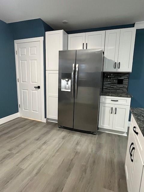 kitchen featuring stainless steel refrigerator with ice dispenser, tasteful backsplash, dark hardwood / wood-style flooring, dark stone counters, and white cabinets