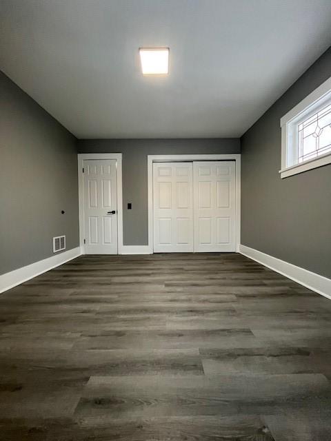 unfurnished bedroom featuring dark hardwood / wood-style flooring and a closet