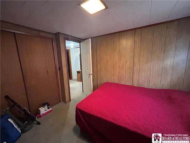 unfurnished bedroom featuring light carpet, a closet, and wood walls