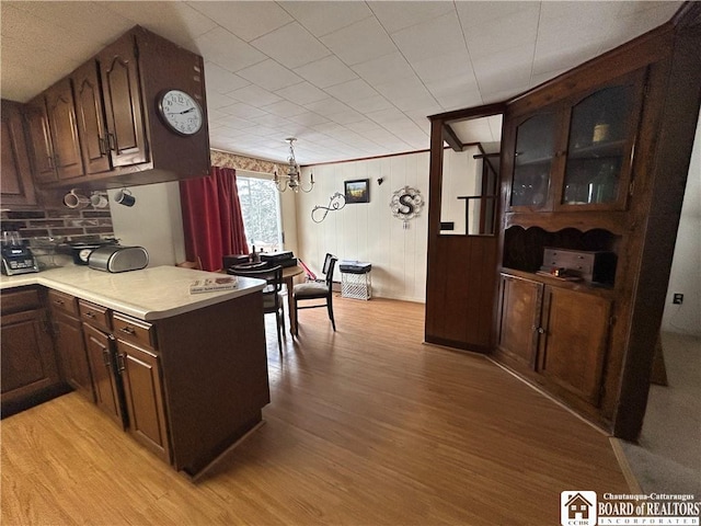 kitchen featuring dark brown cabinetry, hanging light fixtures, light hardwood / wood-style flooring, and a chandelier