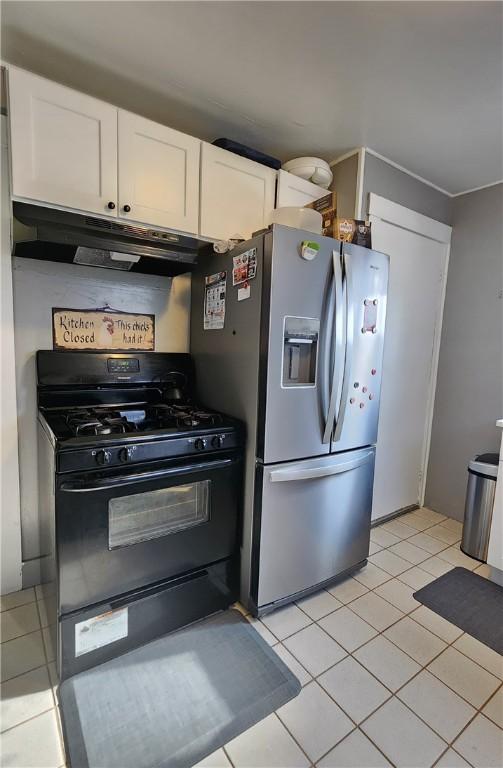 kitchen featuring light tile patterned floors, stainless steel fridge, black gas range, and white cabinets