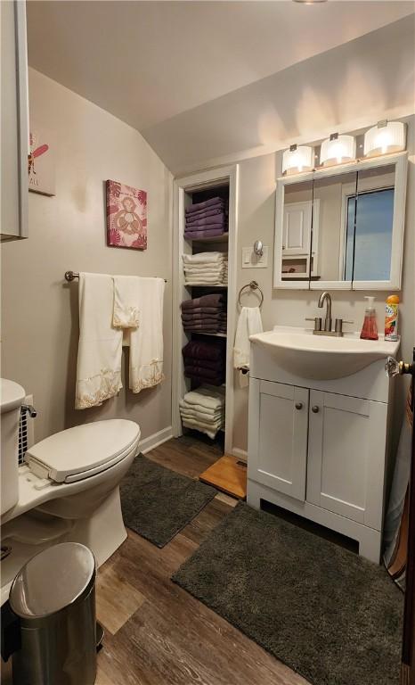 bathroom featuring vanity, wood-type flooring, lofted ceiling, and toilet