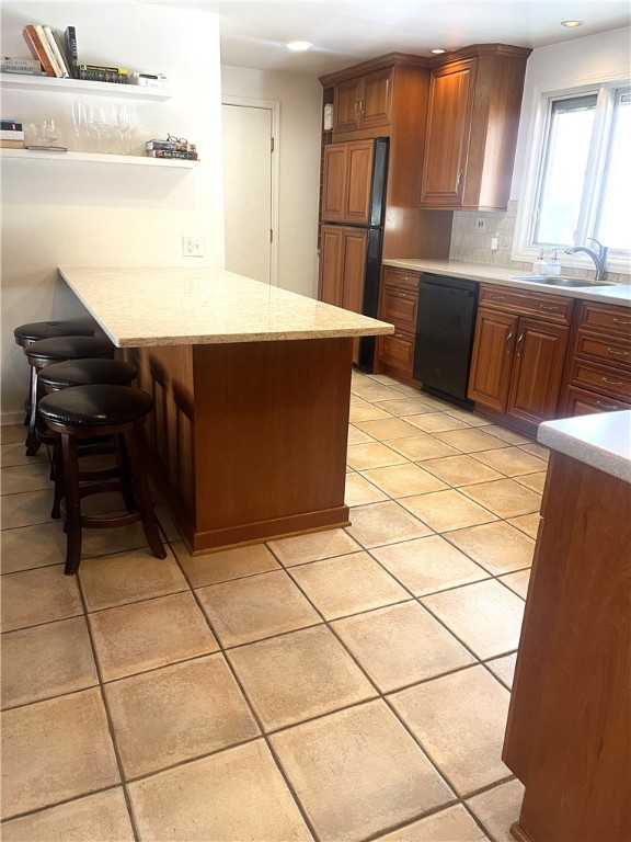 kitchen with dishwasher, a breakfast bar area, decorative backsplash, light tile patterned floors, and kitchen peninsula