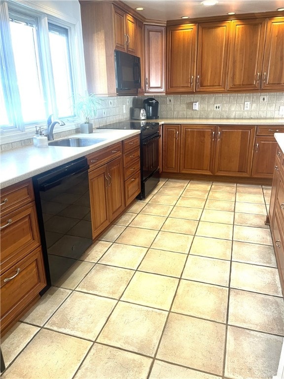 kitchen featuring tasteful backsplash, sink, light tile patterned floors, and black appliances