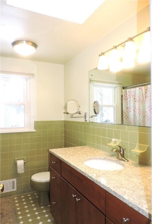 bathroom featuring vanity, toilet, tile walls, and a wealth of natural light