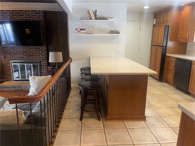 kitchen with light tile patterned floors, a breakfast bar, black dishwasher, paneled refrigerator, and a brick fireplace