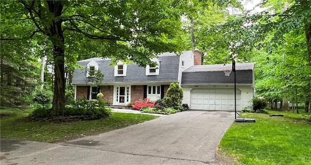 cape cod home featuring a garage and a front lawn