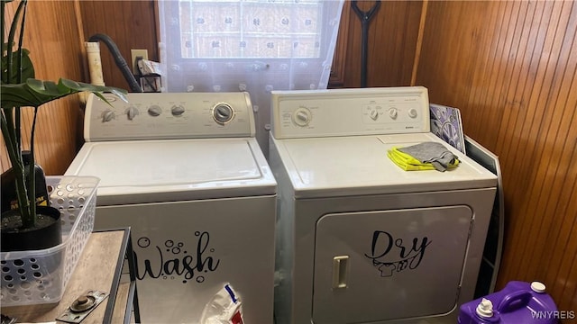 laundry area with wooden walls and washer and dryer