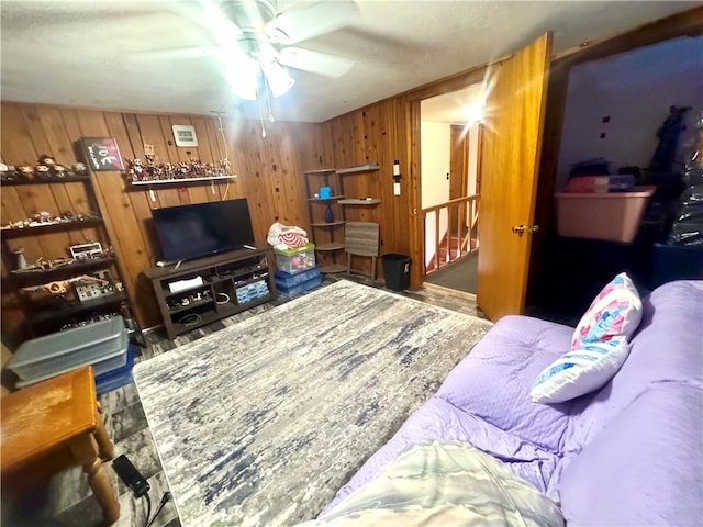 living room featuring ceiling fan and wood walls