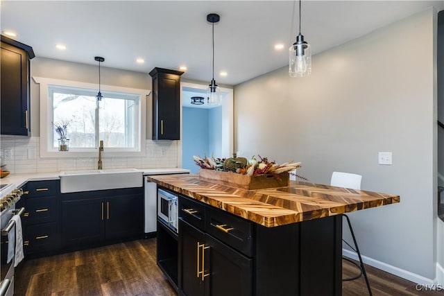 kitchen with sink, wooden counters, a kitchen breakfast bar, stainless steel appliances, and decorative light fixtures